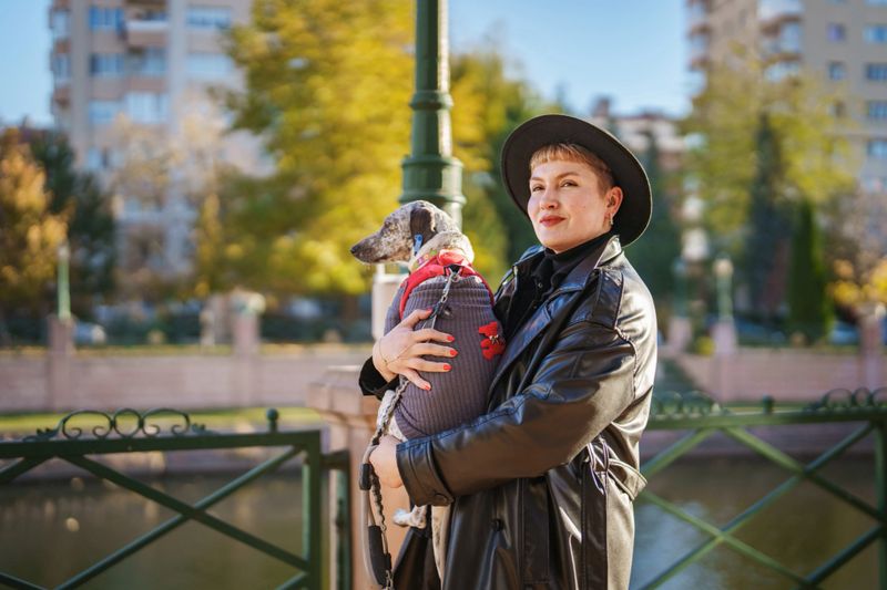 A woman carrying her adopted stray dog in her arms during autumn.