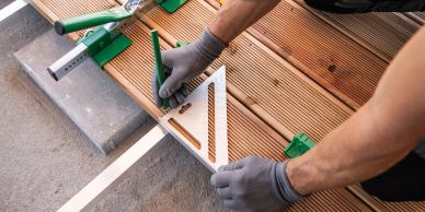Person measuring wood with a square tool.