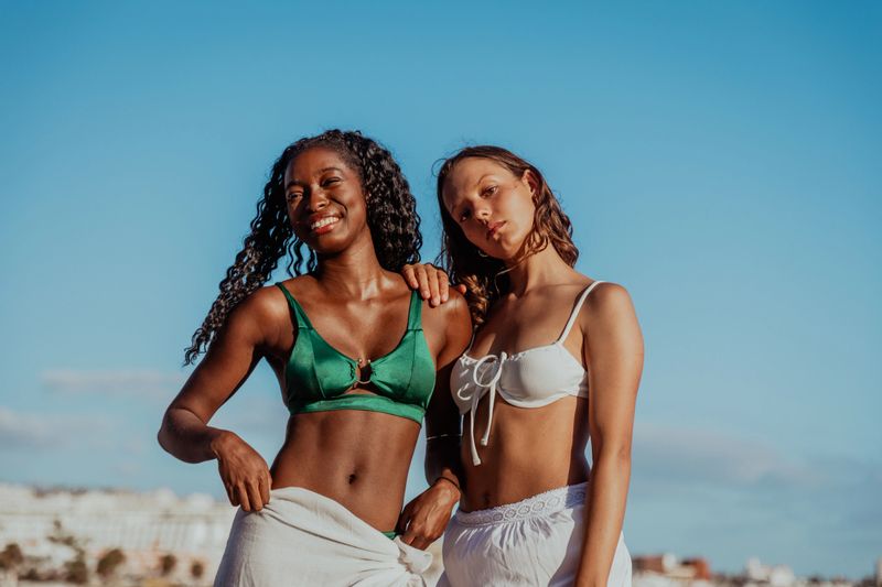 Two women are posing for a picture on a beach, multi ethnic group, carefree feeling