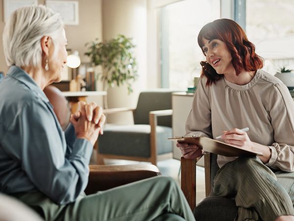 A young counselor talks attentively with an elderly woman in a cozy office.