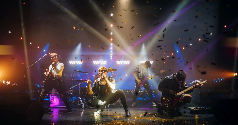 Rock Band Delivers a High-Energy Performance with Lead Guitarist Singing and Playing Electric Guitar in Sunglasses. Vocalist Passionately Singing, Drummer and Bassist Maintaining a Strong Beat