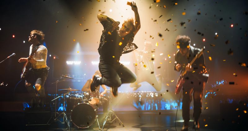 Rock Band Delivers a High-Energy Performance with Lead Guitarist Singing and Playing Electric Guitar in Sunglasses. Vocalist Passionately Singing, Drummer and Bassist Maintaining a Strong Beat