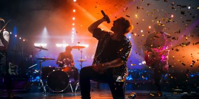 A dynamic band performance with confetti and vibrant lighting.