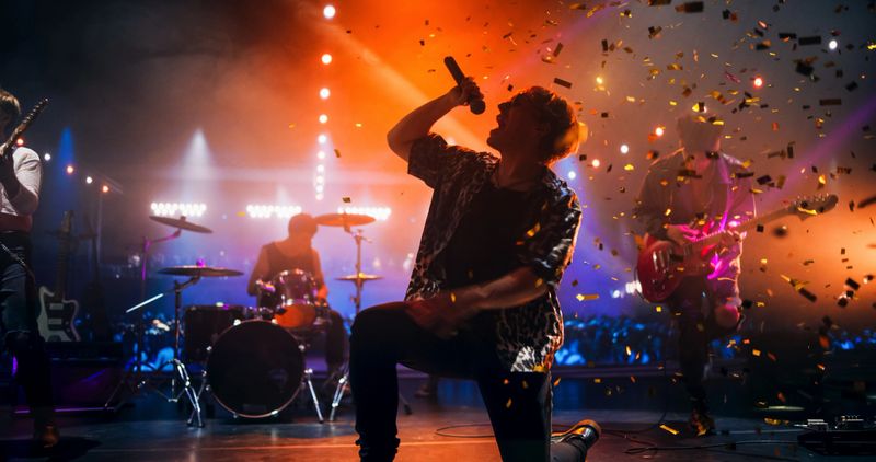 Rock Musicians in Fashionable Outfits Performing Alternative Punk Rock Music on a Nightclub Stage, Passionately Playing Guitars Under Bright Spotlights, Bringing Energy to Cheering Fans