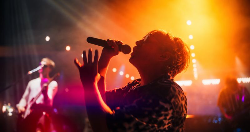 Portrait of a Lead Singer Performing at a Rock Concert Live on Stage with Confetti. Talented Musician Bringing His Unique Attitude, Playing Energetic Rock Hits. Young Band Playing For the Crowd