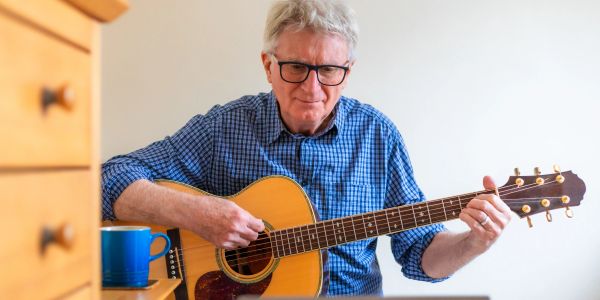 Older man playing guitar indoors.