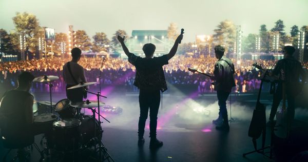 Band performing live on stage with enthusiastic crowd at night.