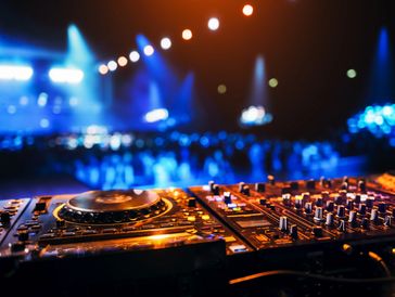 DJ mixing console lit up at a vibrant nightclub with blurred crowd and blue lights.