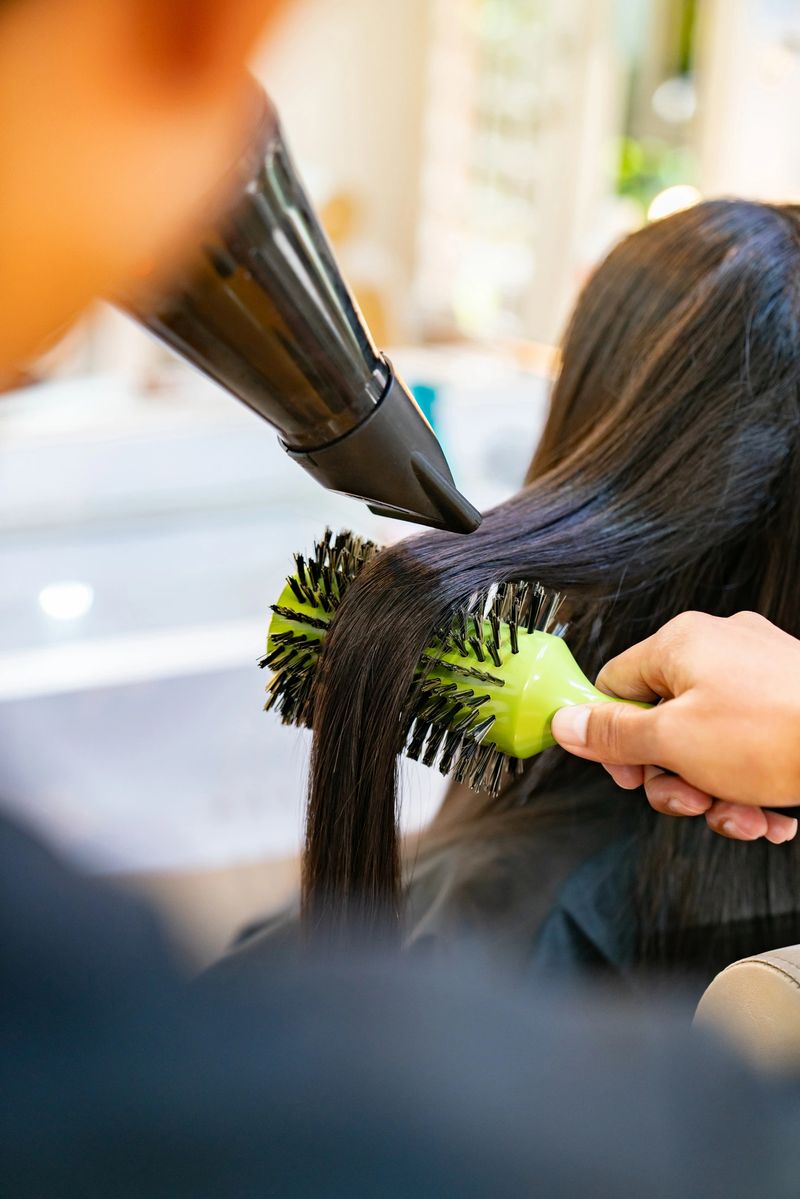 Close-up on a hairdresser blow drying a woman's long hair at the salon - beauty concepts