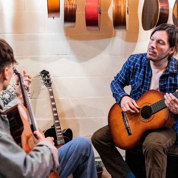Two men playing acoustic guitars indoors.