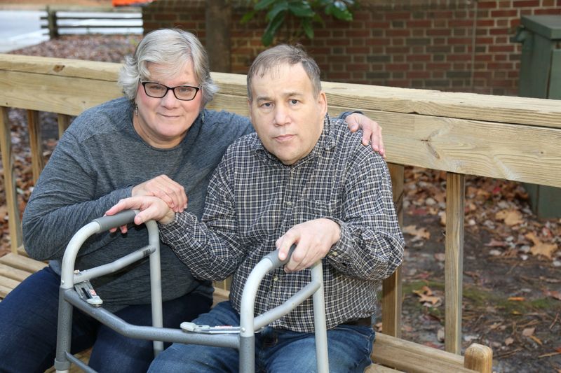 Middle aged man who is also Autistic walks with his walker with the aid of his caretaker who is also his sister.