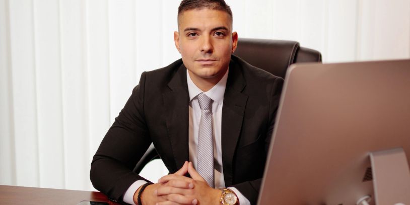 Young businessman in a suit sitting confidently at his desk.
