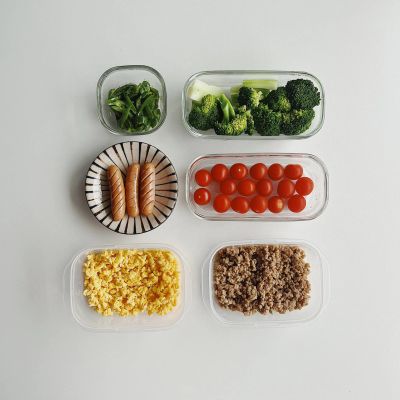 Organized containers of scrambled eggs, ground meat, cherry tomatoes, broccoli, sausages, and greens.
