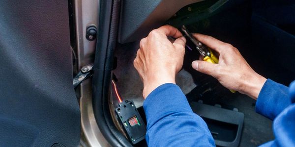 Person repairing car electrical system with screwdriver.