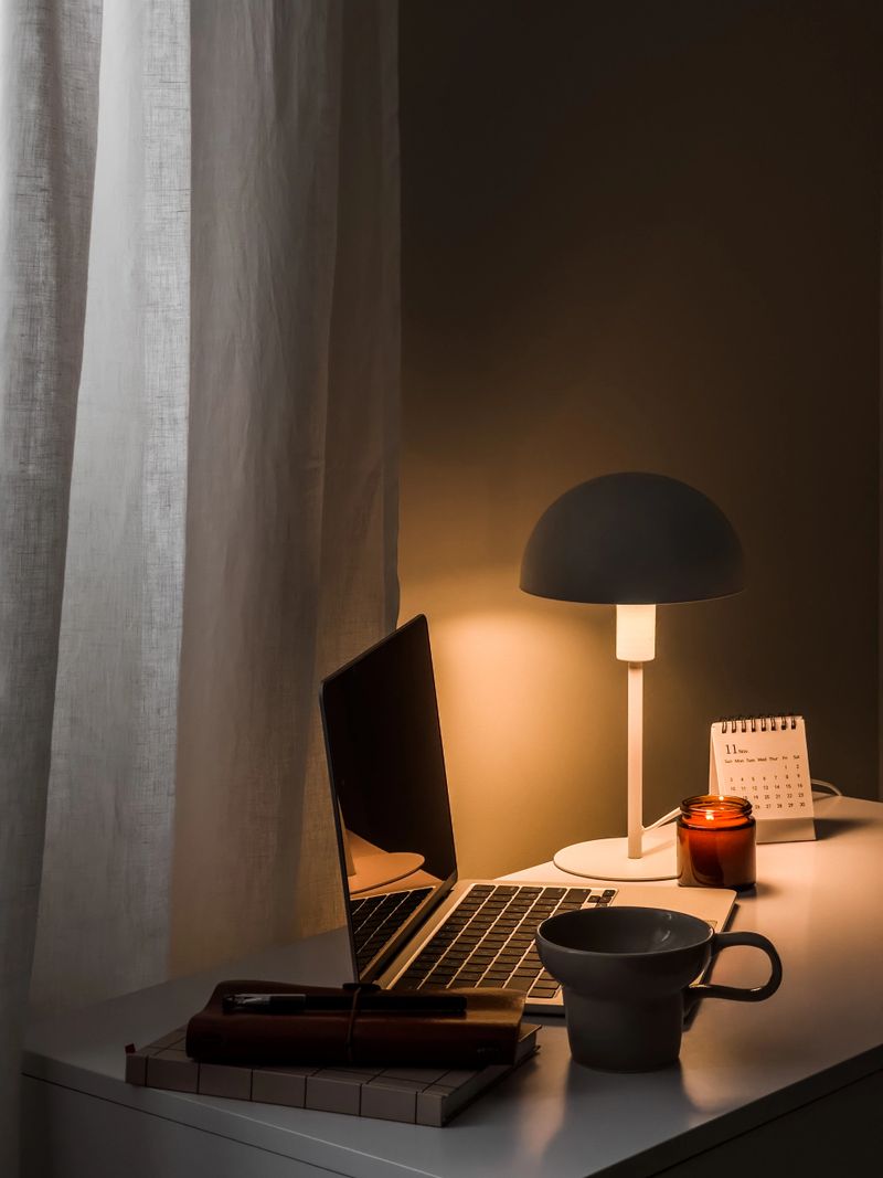 A cozy home evening - a laptop, notebooks, a cup of tea, a lamp on the table in the home office