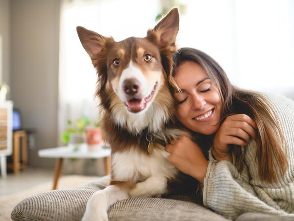 A woman happily hugging her dog indoors.