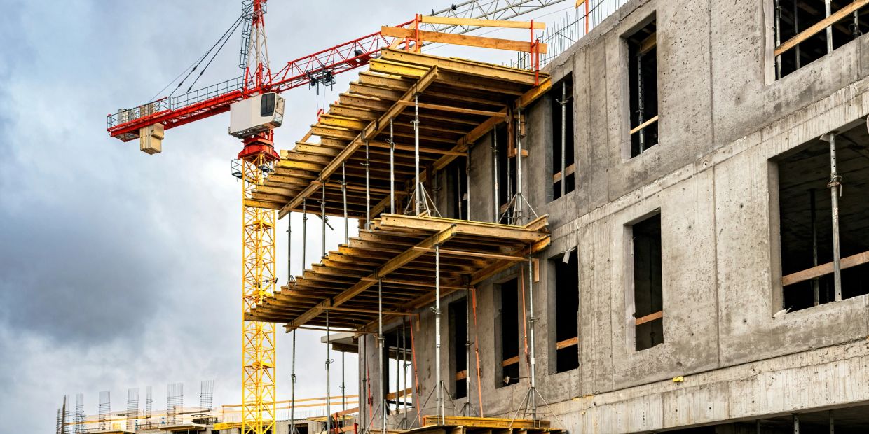 Construction site with crane and concrete building framework.