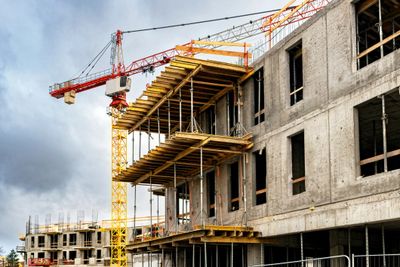 Construction site with cranes and unfinished concrete building.