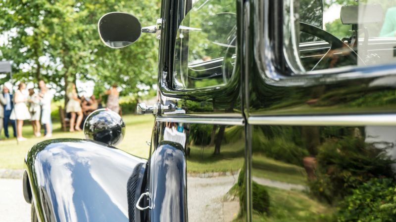 Reflection of Wedding Celebrations on a Classic Black Vintage Car