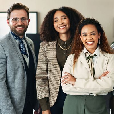 Diverse group of five professionals smiling confidently in an office setting.