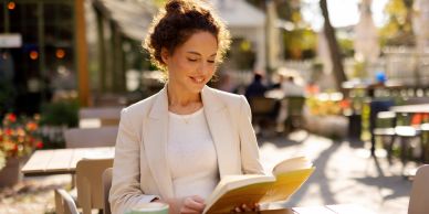 Woman reading a book at an outdoor cafe.