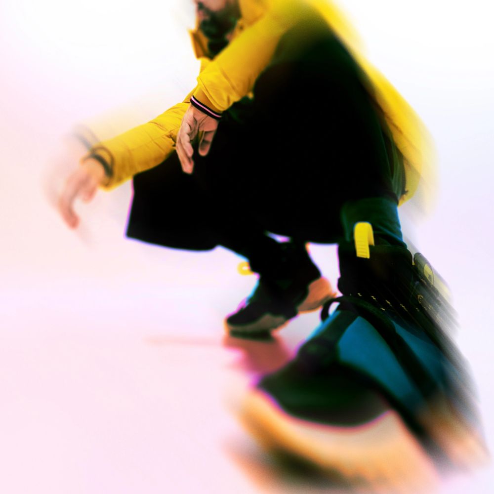 Person wearing a yellow jacket and black shoes in a dynamic, blurred pose.
