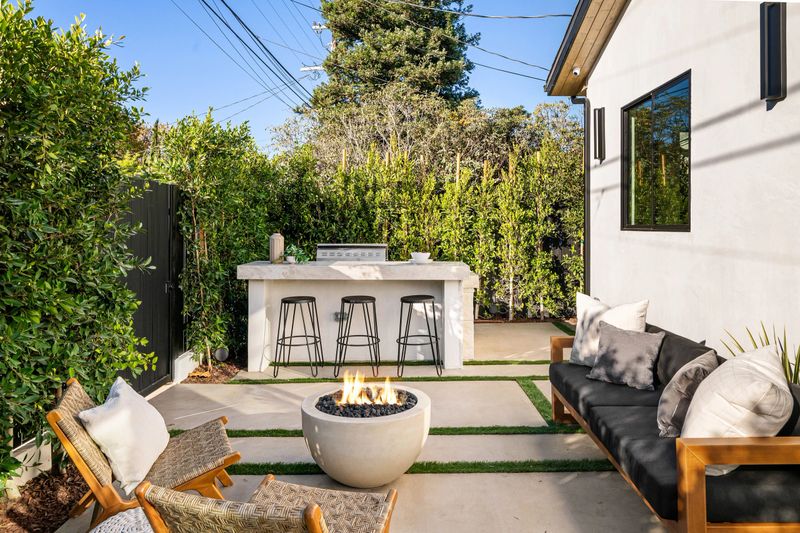 Modern outdoor patio with fire pit, seating, and greenery, perfect for relaxation and gatherings.