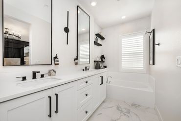 Modern white bathroom with black fixtures and a large mirror.
