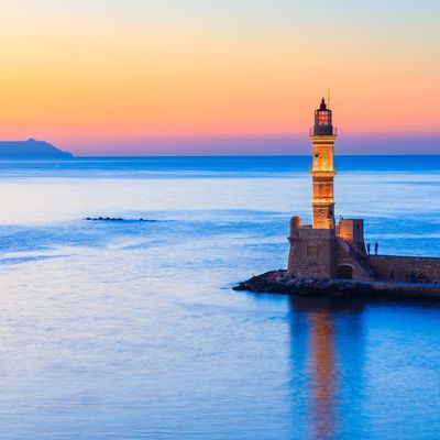 A lighthouse in front of a scenic seascape background.