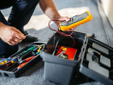 Person using a multimeter with tool kit.