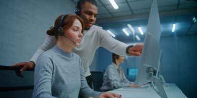 Two customer service workers collaborating at a computer.