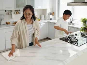 A woman and a boy cleaning a modern kitchen together.