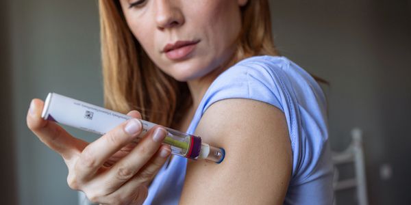 Woman using an insulin pen to inject her arm.