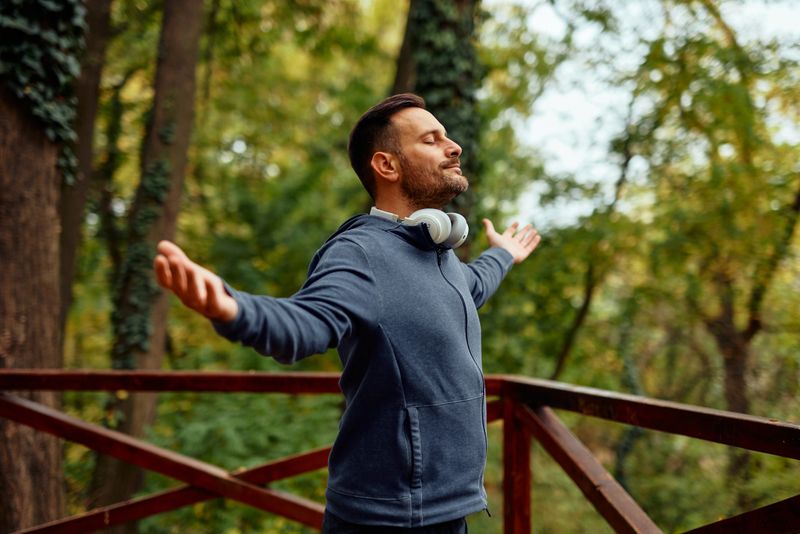 Mid adult man with arms outstretched outdoors