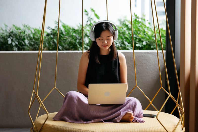 Asian woman is working with her laptop while sitting in a cozy hammock