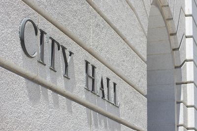 Sign reading 'CITY HALL' on a building wall.