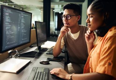 Two people collaborating on coding at a computer.