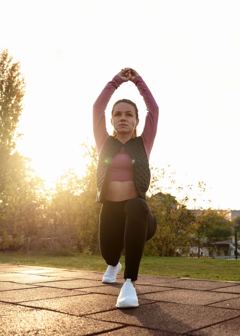 Young woman doing stretching exercises during an outdoor workout. Female runner warming up before a run.