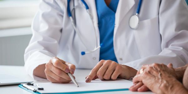 Doctor consulting patient and writing notes.