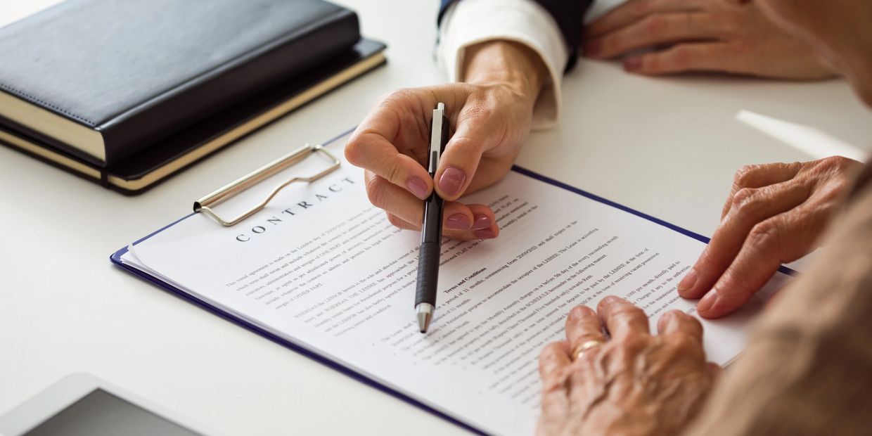 Person explaining contract details with a pen to another individual.