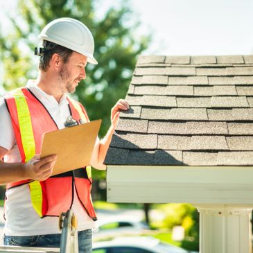Construction worker inspecting roof shingles with clipboard outdoors.