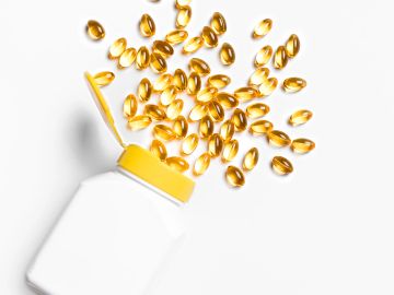 Yellow capsules spilling from a white bottle with a yellow lid.