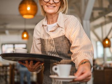Smiling waitress serving coffee in a cafe.
