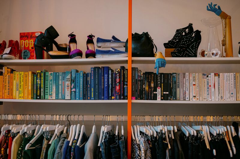 Shoes, books and clothes on shelves and rails in a vintage store