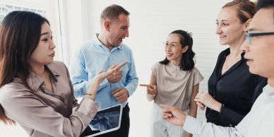 Five colleagues engaged in a lively discussion in a bright office.