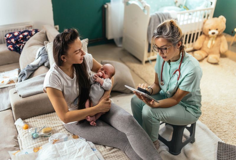 Female doctor at house visit,checking up newborn baby boy