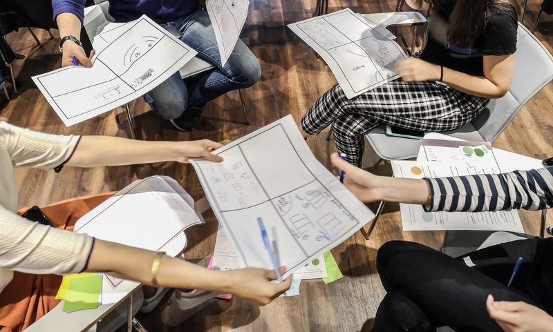 A dynamic design workshop takes place with participants brainstorming ideas. Colorful papers reveal collaborative creativity in a lively and engaging atmosphere.