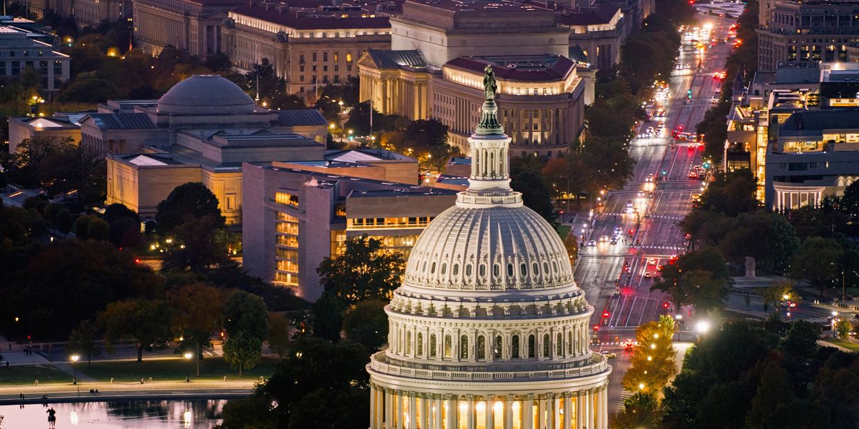 Night view of the illuminated U.S. Capitol building and surrounding city streets.