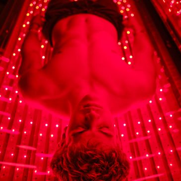 Shirtless man lying under red lights
