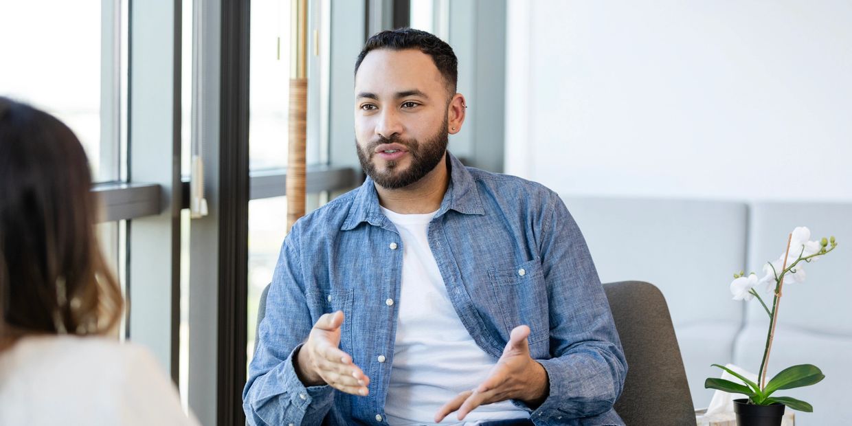 Man in blue shirt engaged in a serious conversation indoors.